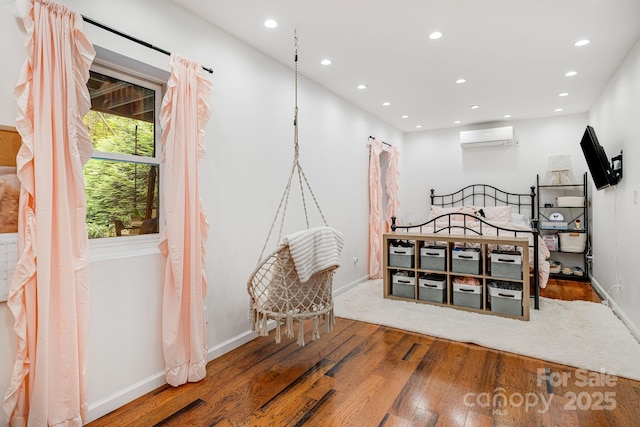 bedroom with hardwood / wood-style flooring, an AC wall unit, recessed lighting, and baseboards