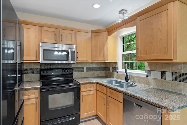 kitchen with appliances with stainless steel finishes, a sink, light brown cabinets, light stone counters, and tasteful backsplash
