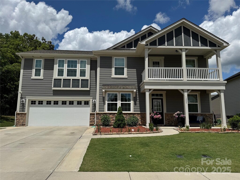 1205 Aiken Cross Ln, Indian Trail, NC 28079 - craftsman-style home featuring a balcony, driveway, stone siding, a porch, and a front yard