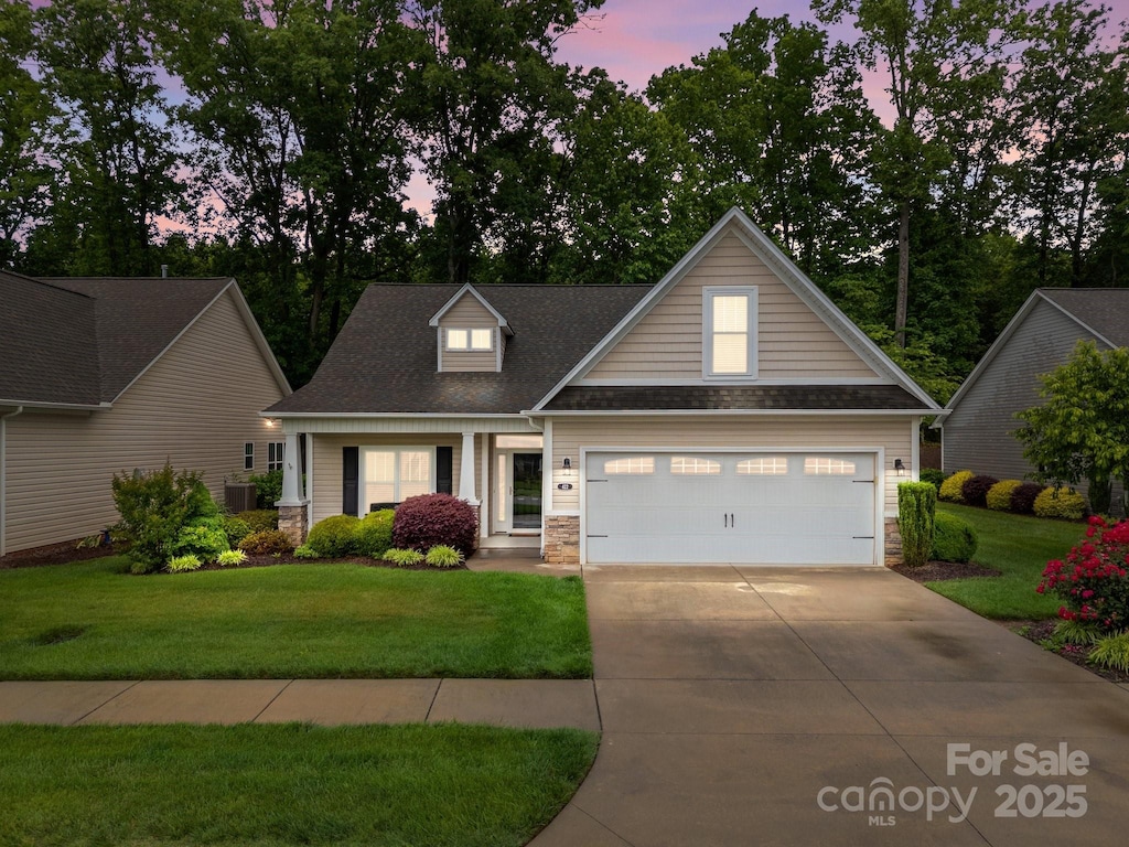 422 Drake Ln, Salisbury, NC 28146 - view of front facade featuring a front lawn, concrete driveway, stone siding, a garage, and roof with shingles