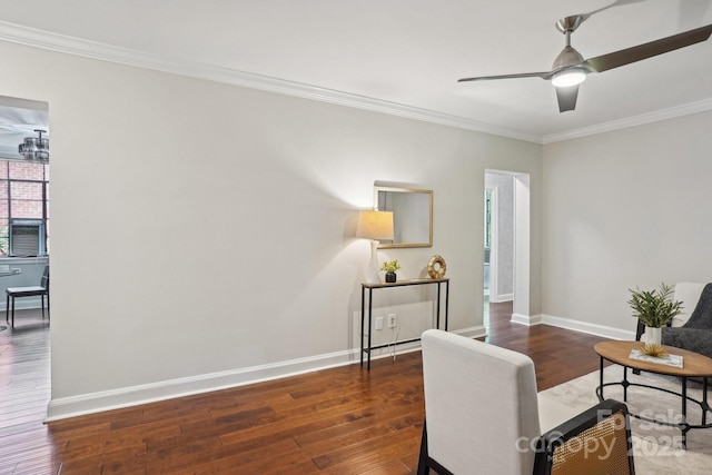 living area with wood finished floors, ornamental molding, baseboards, and ceiling fan
