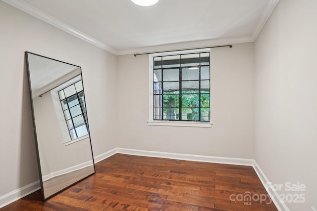 empty room with ornamental molding, wood finished floors, and baseboards