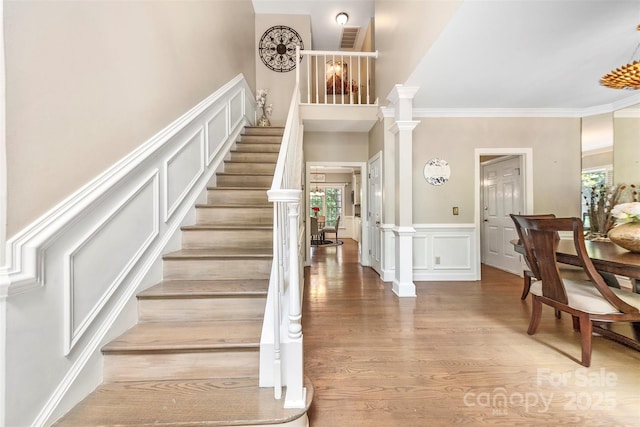 4846 Deer Cross Trl, Charlotte, NC 28269 - stairway with a decorative wall, wood finished floors, ornamental molding, wainscoting, and a high ceiling