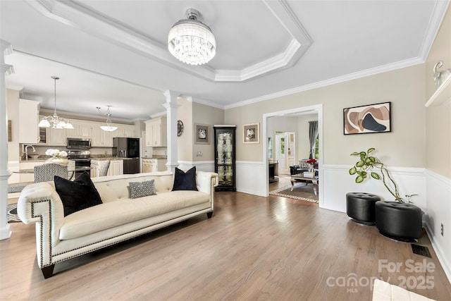 4846 Deer Cross Trl, Charlotte, NC 28269 - living area with a chandelier, decorative columns, wainscoting, crown molding, and wood finished floors