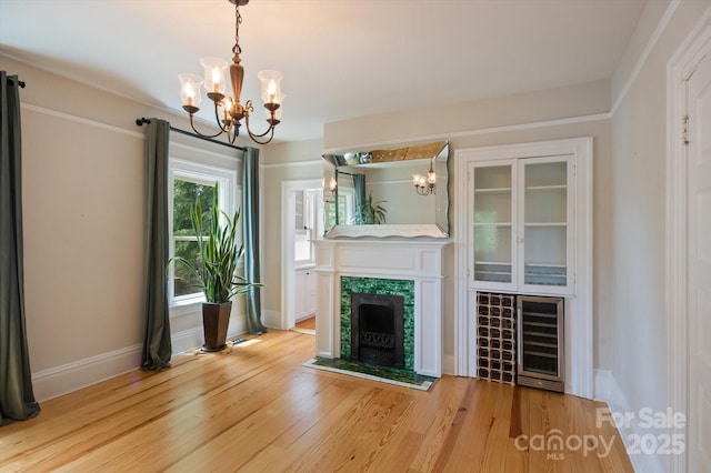 31 Jefferson Dr, Asheville, NC 28801 - unfurnished living room featuring a chandelier, wine cooler, a tiled fireplace, and light wood-type flooring