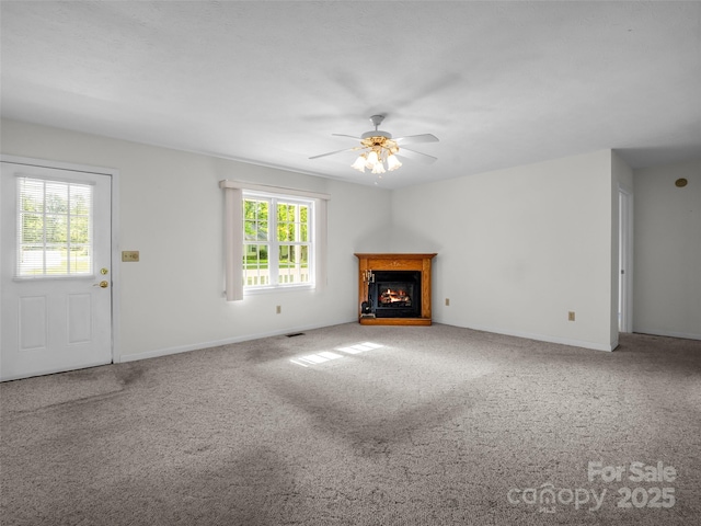 77 Simmons Dr, East Flat Rock, NC 28726 - unfurnished living room with a lit fireplace, carpet, a ceiling fan, and baseboards