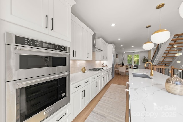 158 Mattoon St, Charlotte, NC 28216 - kitchen with stainless steel appliances, a sink, wall chimney exhaust hood, backsplash, and white cabinets