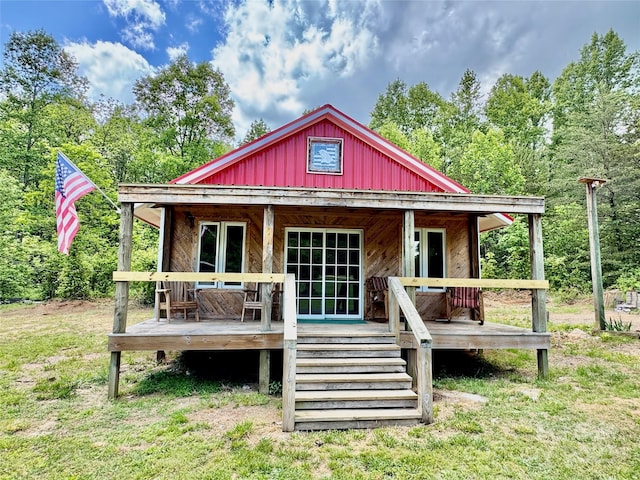 rear view of house with board and batten siding, covered porch, and stairway