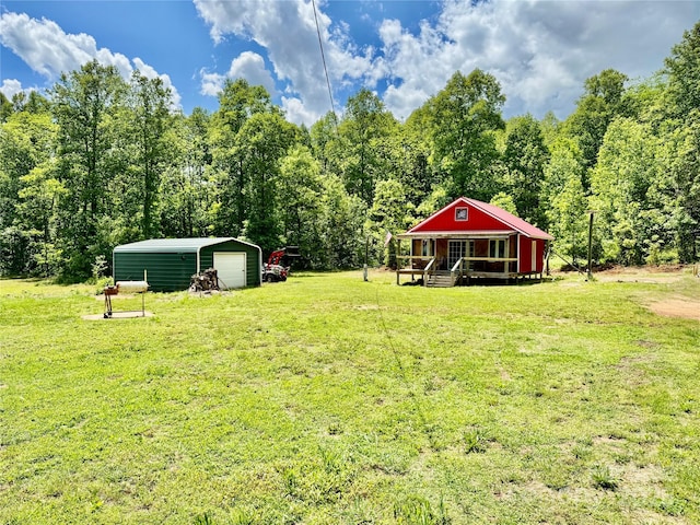 view of green lawn featuring an outbuilding, a garage, and a view of trees