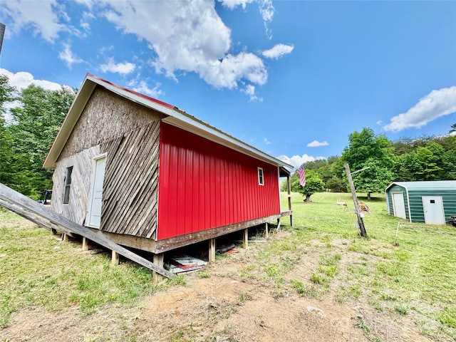 view of side of property with an outbuilding, a lawn, and a shed