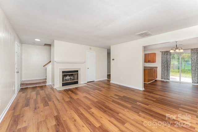 unfurnished living room with wood finished floors, baseboards, a chandelier, and recessed lighting