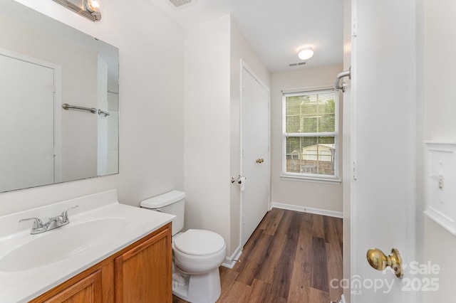 bathroom with wood finished floors, toilet, vanity, and baseboards