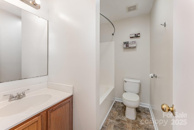 full bath featuring toilet, vanity, baseboards, stone finish flooring, and shower / bath combination