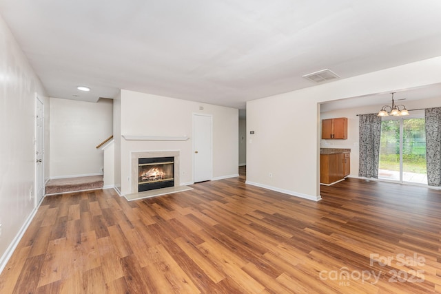 unfurnished living room with wood finished floors, baseboards, a chandelier, and recessed lighting