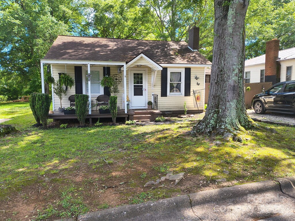 bungalow-style house with a chimney, covered porch, and a front yard