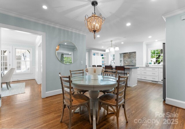 236 Wales Ave, Charlotte, NC 28209 - dining space with a chandelier, baseboards, ornamental molding, wood finished floors, and recessed lighting