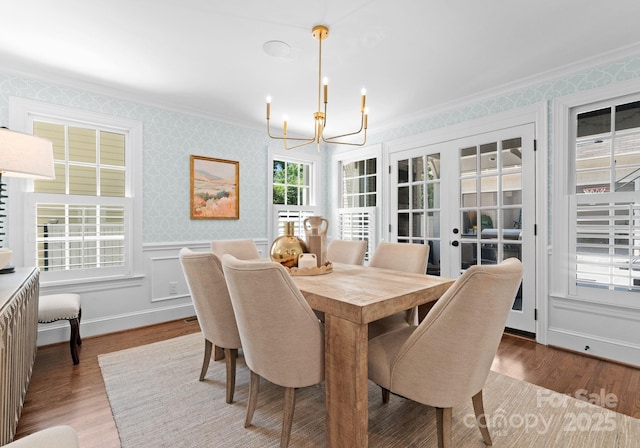 236 Wales Ave, Charlotte, NC 28209 - dining space featuring a chandelier, crown molding, wallpapered walls, french doors, and wood finished floors