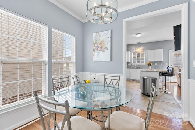 9775 Mallard Glen Dr, Charlotte, NC 28262 - dining room featuring light wood-type flooring, a chandelier, wainscoting, and crown molding