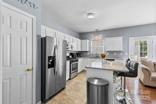 9775 Mallard Glen Dr, Charlotte, NC 28262 - kitchen with appliances with stainless steel finishes, a kitchen breakfast bar, white cabinets, a sink, and light stone countertops
