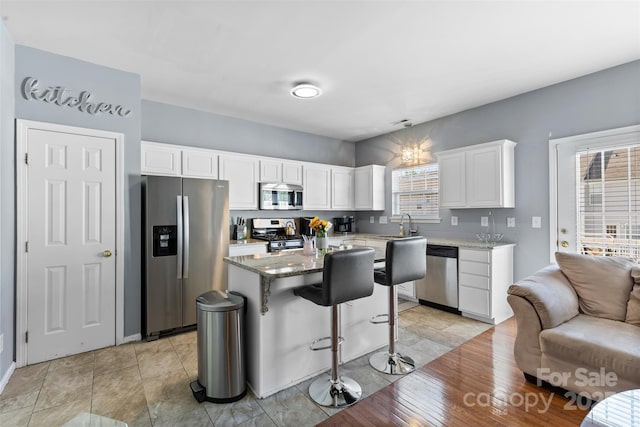 9775 Mallard Glen Dr, Charlotte, NC 28262 - kitchen featuring stainless steel appliances, white cabinetry, open floor plan, a kitchen breakfast bar, and a kitchen island