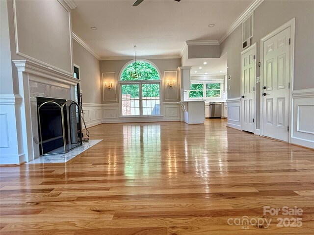 456 Brook Valley Ct NE, Concord, NC 28025 - unfurnished living room with a decorative wall, light wood finished floors, a fireplace, crown molding, and a ceiling fan