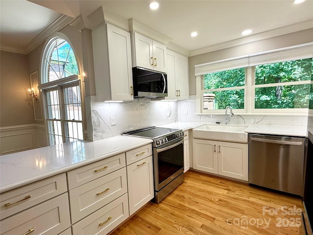 456 Brook Valley Ct NE, Concord, NC 28025 - kitchen with stainless steel appliances, a sink, ornamental molding, white cabinetry, and light wood finished floors
