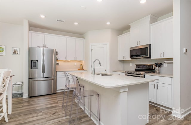 941 Rachel Anne Dr, Belmont, NC 28012 - kitchen featuring appliances with stainless steel finishes, a sink, light wood-style floors, white cabinets, and backsplash