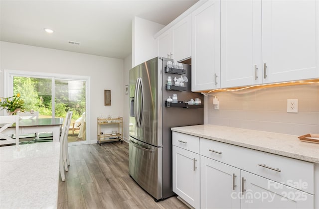 941 Rachel Anne Dr, Belmont, NC 28012 - kitchen featuring stainless steel fridge, decorative backsplash, white cabinets, light wood-style floors, and light stone counters