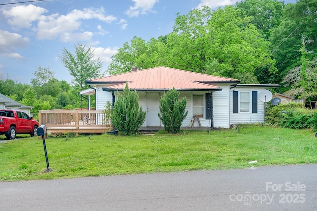 view of front of property with a front lawn, metal roof, and a wooden deck