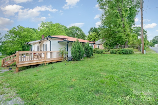 view of grassy yard with a wooden deck