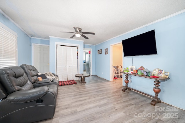 living area featuring crown molding, light wood finished floors, a ceiling fan, and a textured ceiling