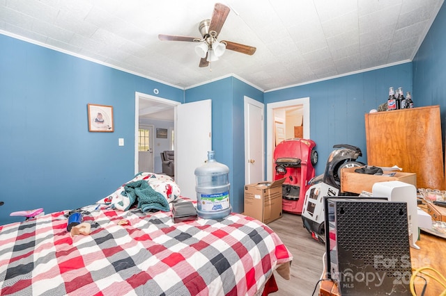 bedroom featuring light wood-style flooring, ornamental molding, and a ceiling fan