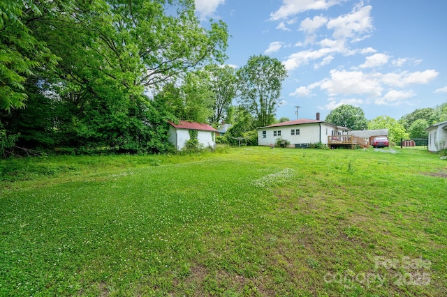 view of grassy yard featuring a shed, an outbuilding, and a wooden deck