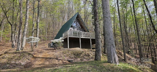 rear view of house with a deck and a view of trees