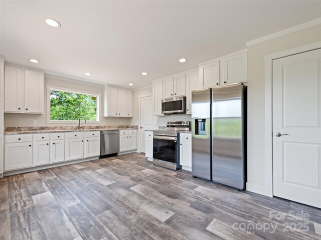 255 Thompson Cove Rd, Clyde, NC 28721 - kitchen featuring appliances with stainless steel finishes, a sink, light wood finished floors, white cabinets, and recessed lighting