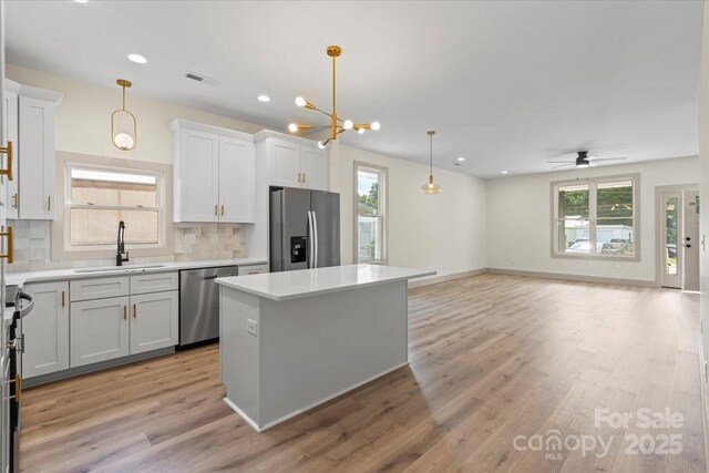 kitchen with appliances with stainless steel finishes, a sink, healthy amount of natural light, a kitchen island, and recessed lighting