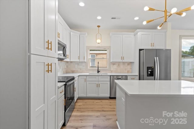 kitchen featuring stainless steel appliances, a sink, plenty of natural light, a chandelier, and recessed lighting