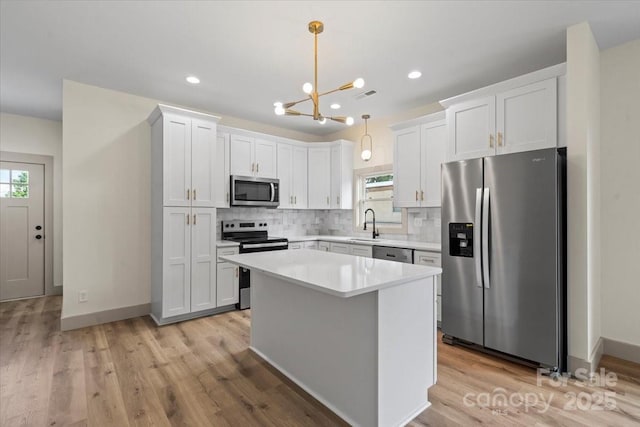 kitchen featuring stainless steel appliances, decorative backsplash, a chandelier, light countertops, and white cabinetry