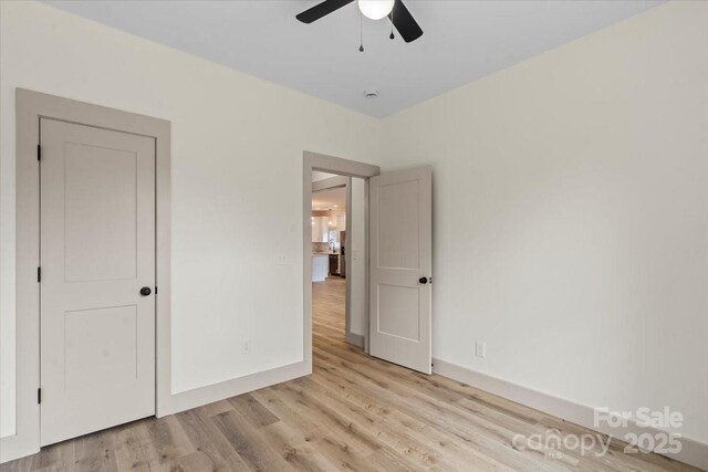 unfurnished bedroom featuring light wood finished floors, baseboards, and ceiling fan