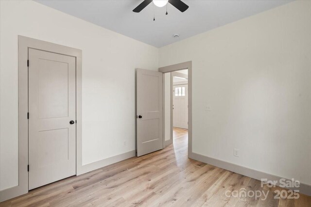 unfurnished bedroom featuring light wood finished floors, baseboards, and ceiling fan