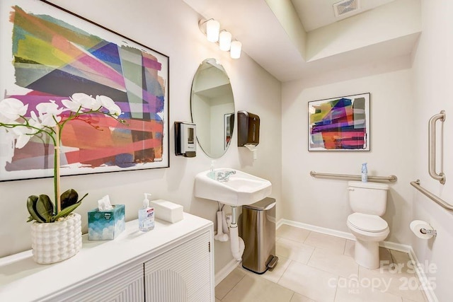 bathroom featuring toilet, tile patterned floors, baseboards, and a sink