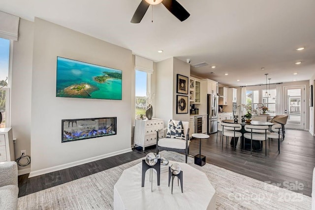 living room with dark wood-type flooring, ceiling fan, recessed lighting, baseboards, and wine cooler