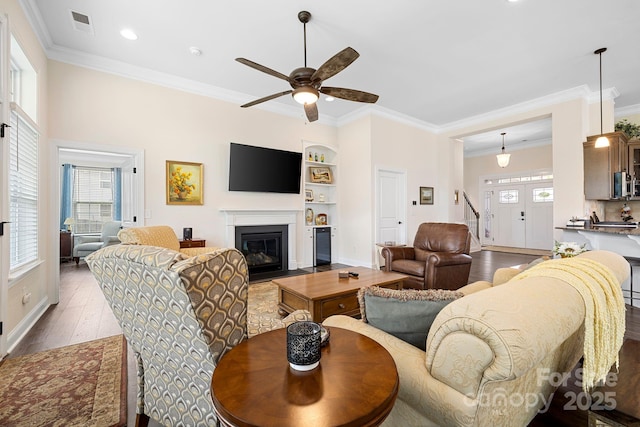 7016 Bareland Rd, Fort Mill, SC 29707 - living room with wood finished floors, a ceiling fan, stairs, ornamental molding, and a fireplace with flush hearth