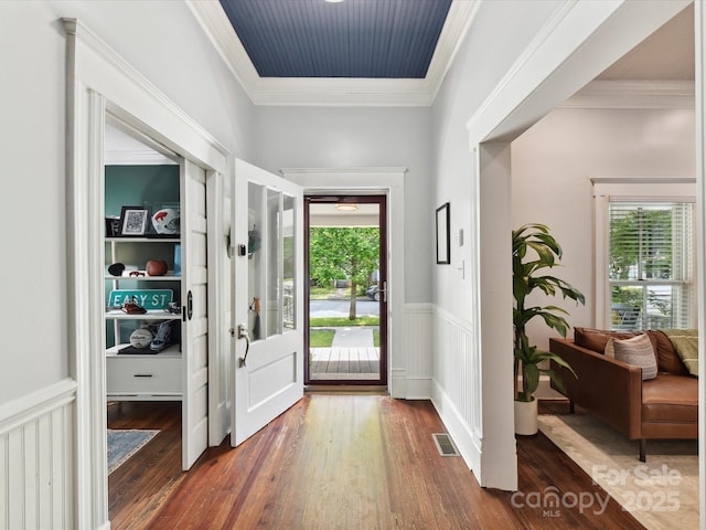 foyer with wood finished floors, wainscoting, and ornamental molding