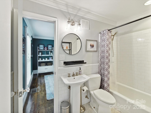 bathroom featuring crown molding, toilet, tile walls, shower / bath combo with shower curtain, and wood finished floors