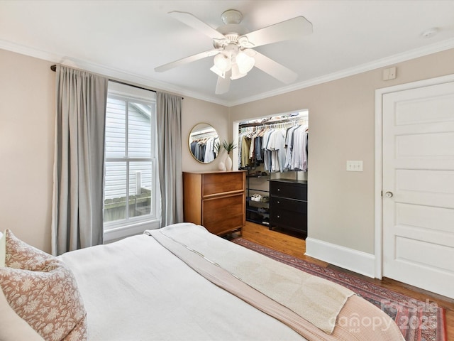 bedroom with wood finished floors, ornamental molding, a closet, baseboards, and ceiling fan