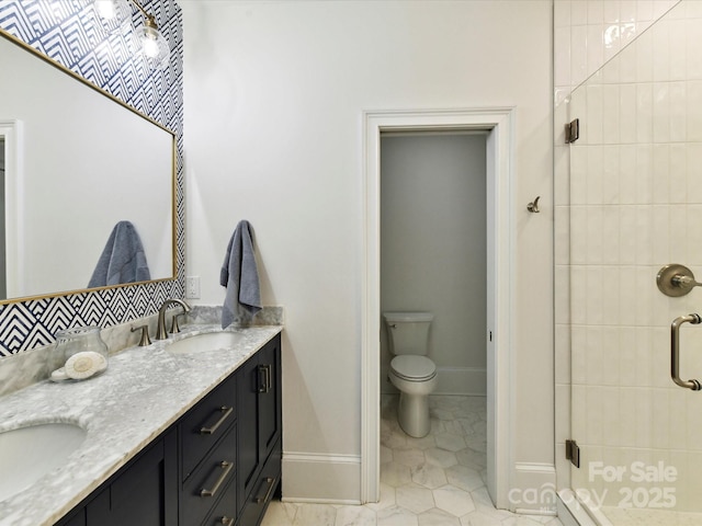 bathroom featuring a stall shower, baseboards, double vanity, toilet, and tile patterned flooring