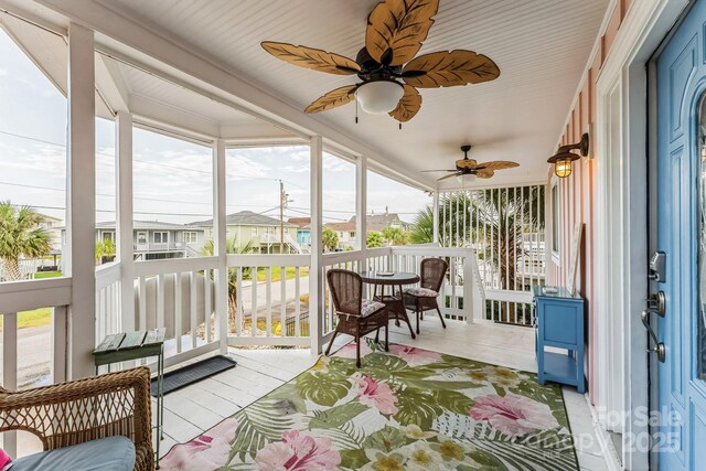 sunroom / solarium featuring ceiling fan, healthy amount of natural light, and a residential view