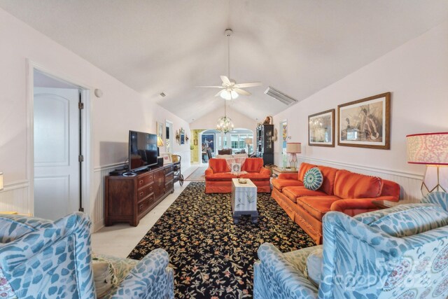 living area with a chandelier, a ceiling fan, vaulted ceiling, a wainscoted wall, and a decorative wall