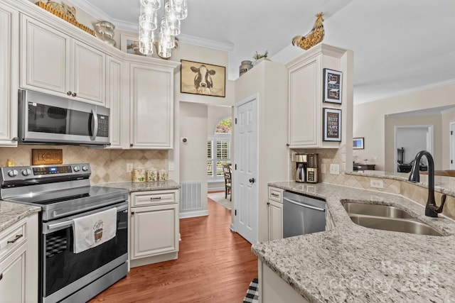 149 Harbor Landing Dr, Mooresville, NC 28117 - kitchen with appliances with stainless steel finishes, a sink, ornamental molding, backsplash, and light wood-style flooring